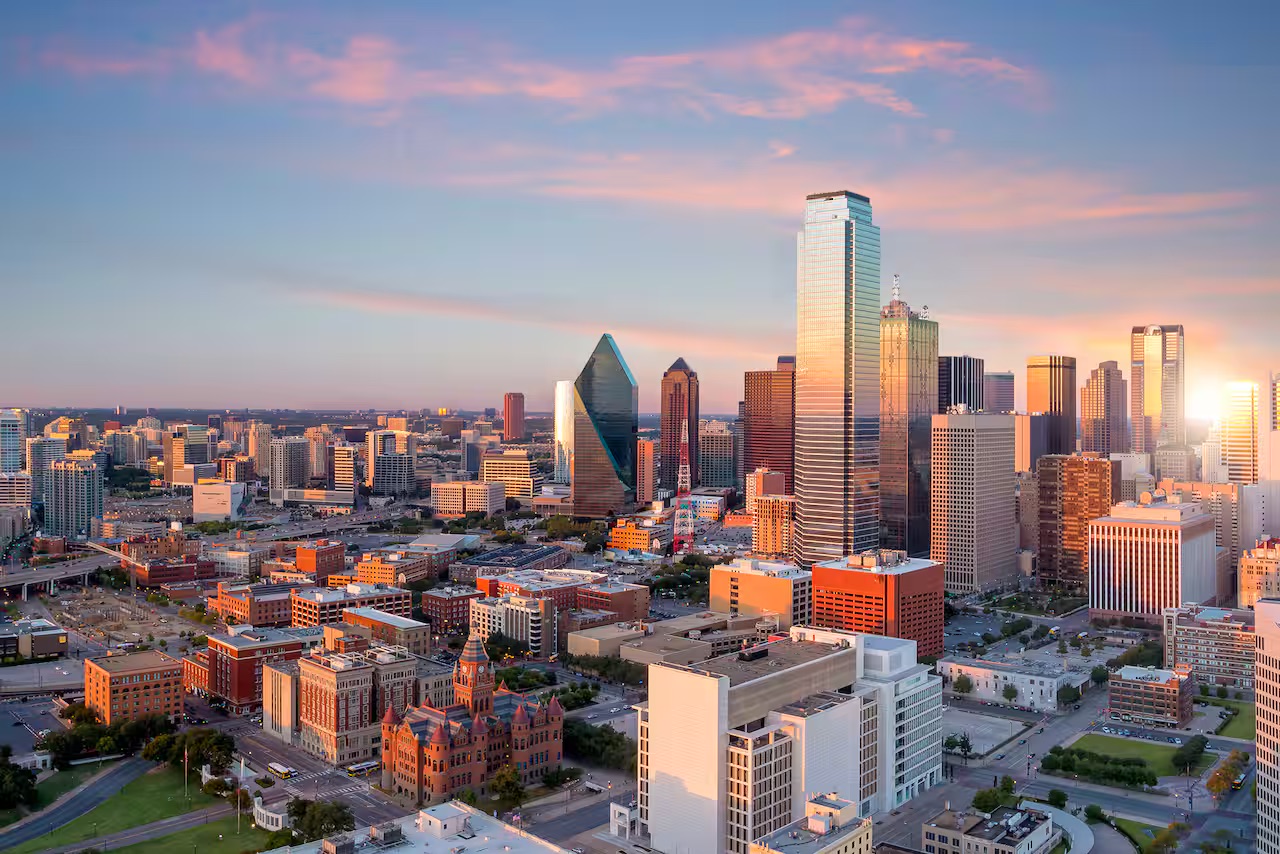Dallas, Texas skyline at sunset featuring downtown skyscrapers and modern city architecture.